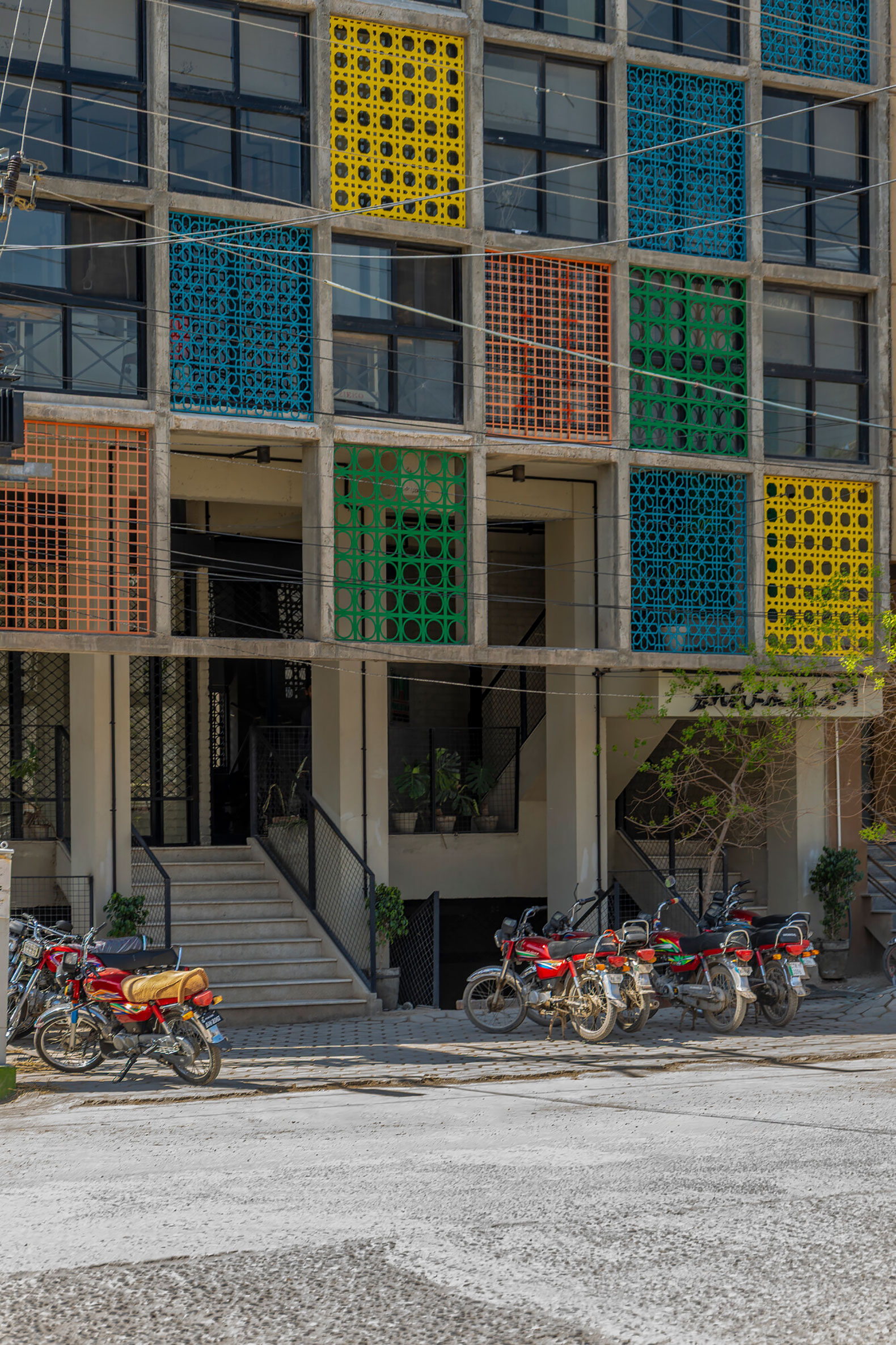 Entrance to the building, whose facade is a finetuned layering of concrete structural elements, metal frames, jaalis and smaller window panes. Aga Khan Trust for Culture / Usman Saqib Zuberi.