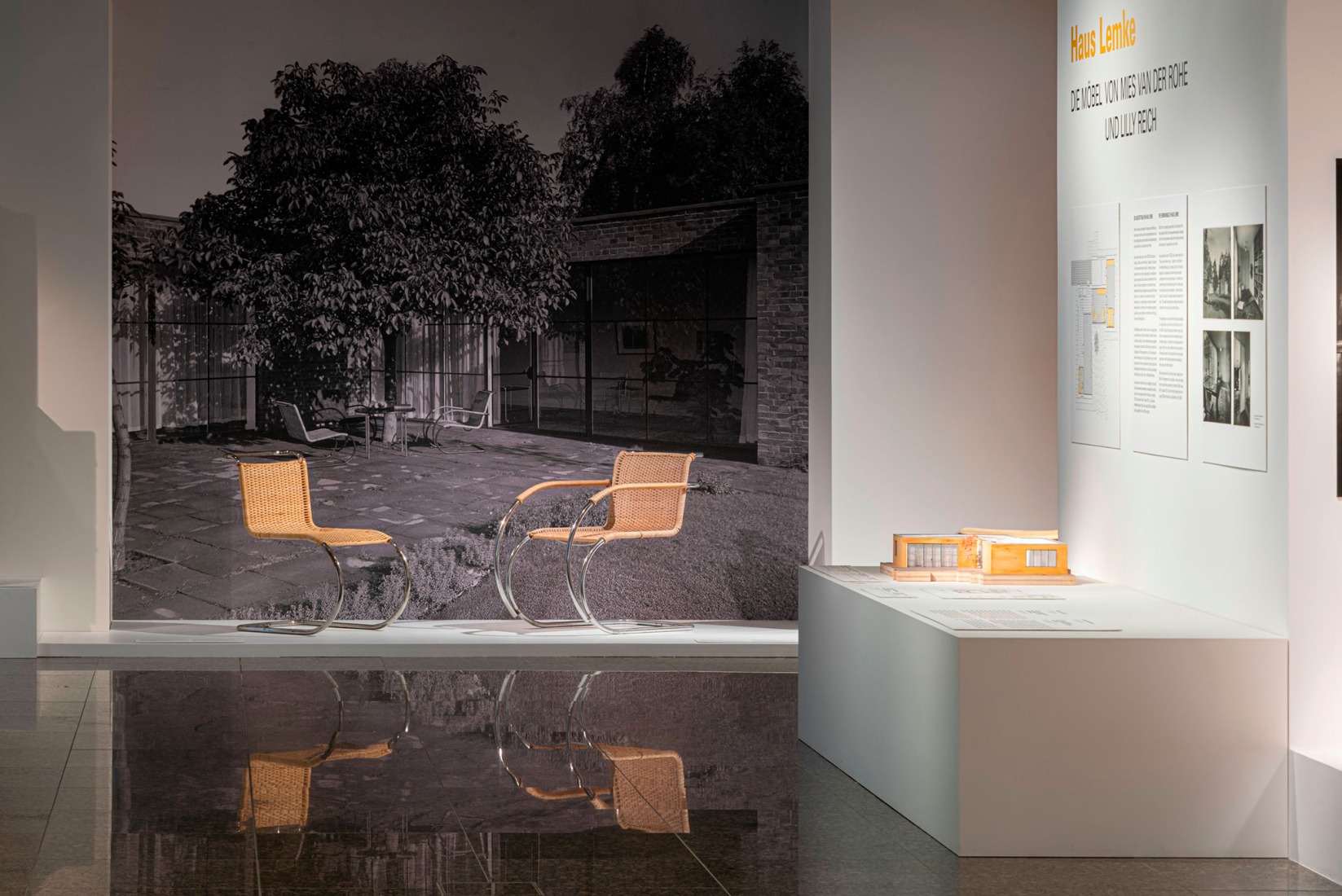 Presentación de mobiliario de tubo de acero basado en un diseño de Mies van der Rohe (1927), con la fotografía publicitaria de Gebr. Thonet con Haus Lemke (1934) al fondo. Fotografía por Staatliche Museen zu Berlin, Kunstgewerbemuseum / Stephan Klonk.