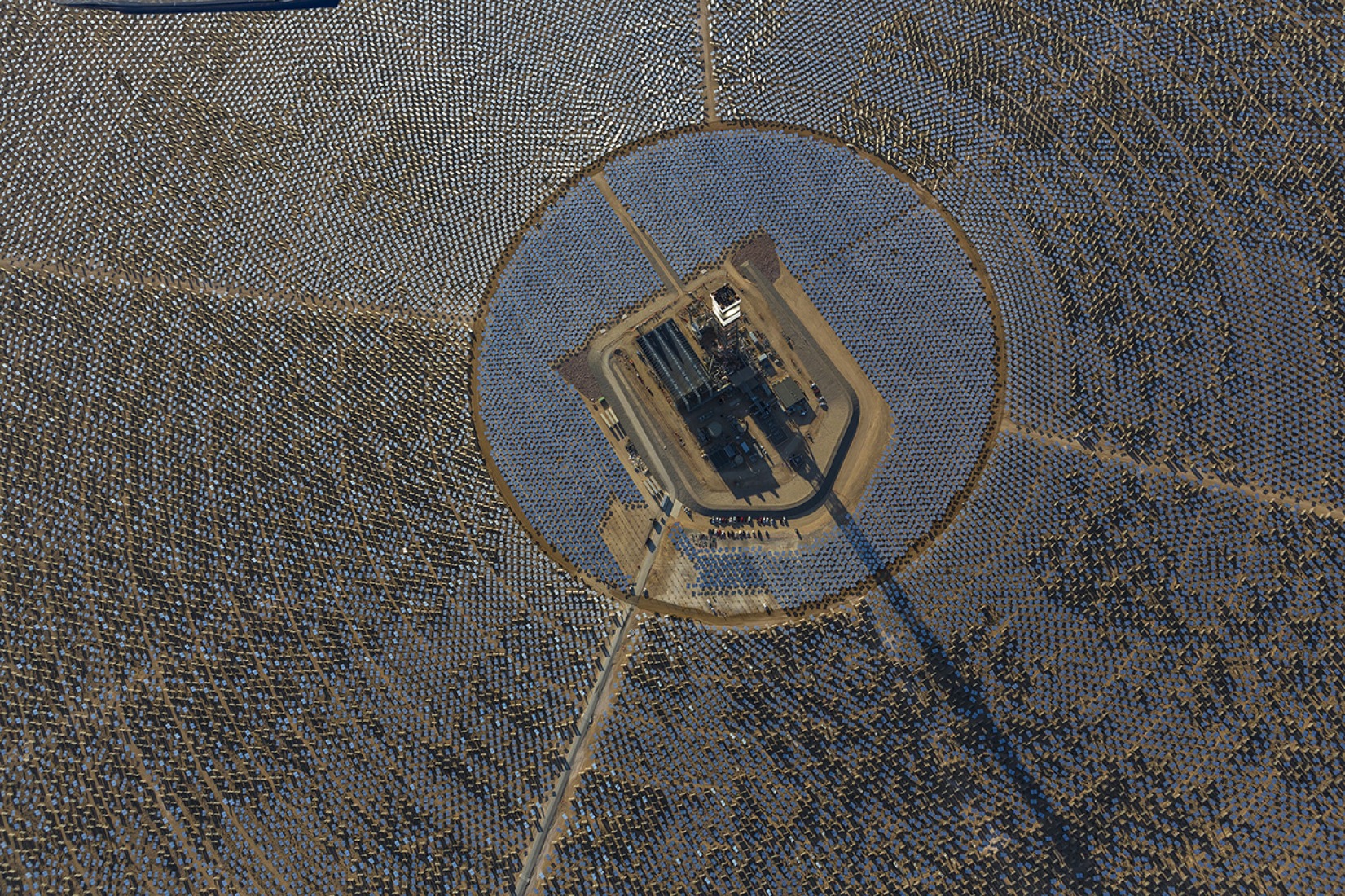 An aerial view of Tower 1 and its heliostats at the Ivanpah Solar Power Facility. The top of Tower 1's is "lit" as steam blow tests are in progress. Image courtesy of Ivanpah. 