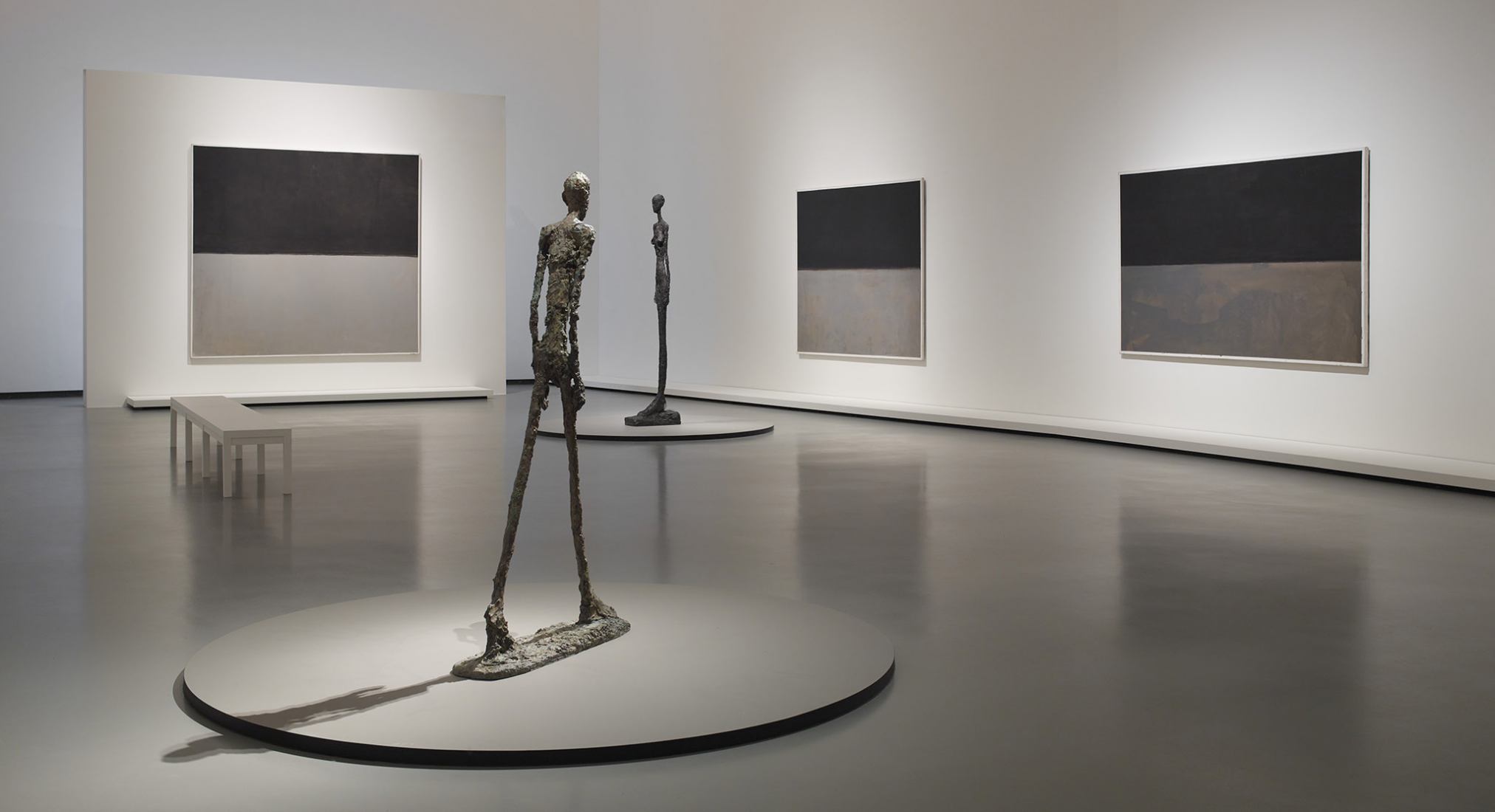 Left to right / Mark Rothko Untitled, 1969 Untitled, 1969 Untitled, 1969 Sculptures / Alberto Giacometti L'Homme qui marche I, 1960 Grande Femme III, 1960. The first retrospective in France dedicated to Mark Rothko, at the Louis Vuitton Foundation. Courtesy of Louis Vuitton Foundation.