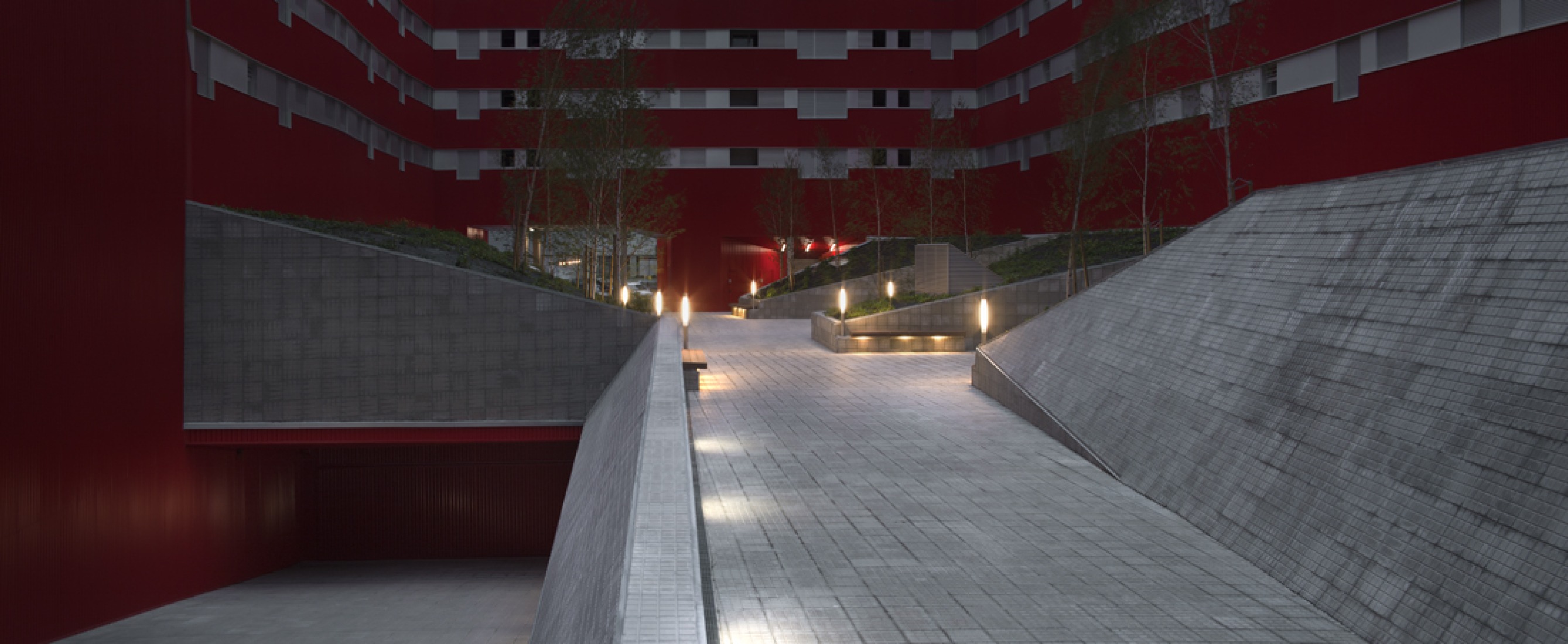 Vista nocturna y acceso a garaje desde plaza interior. 242 viviendas de protección ofcial por Iñaki Garai Zabala (ACXT Architects). Fotografía © Aitor Ortiz.
