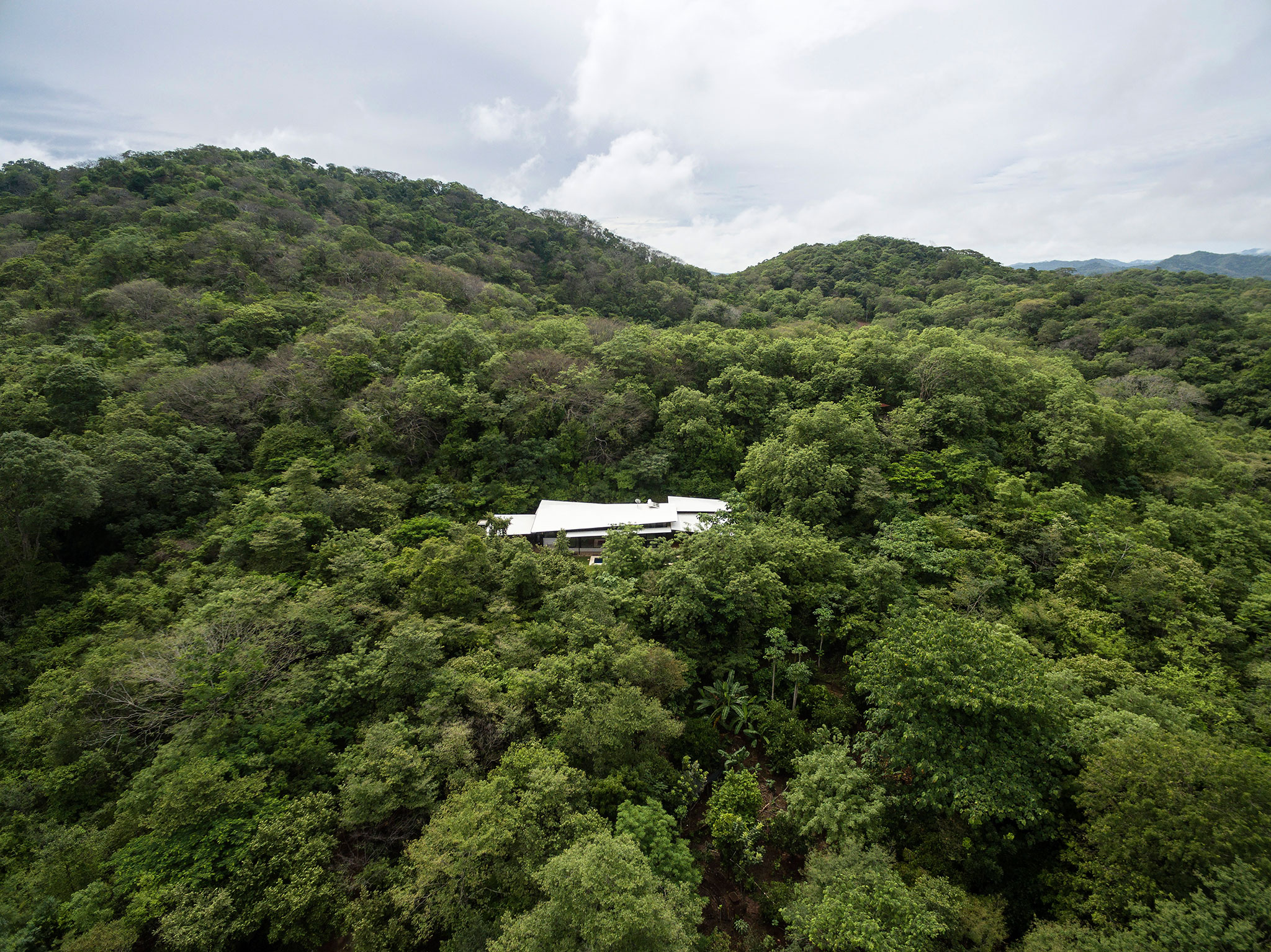 Open to the landscape, under white plans. Casa las Hojas by