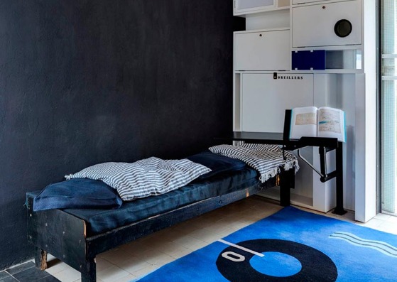 La alcoba en la sala de estar con cabecero, almohada armario y bandeja de libro, restaurado a su condición original, y la alfombra Marine diseñada por Gray
