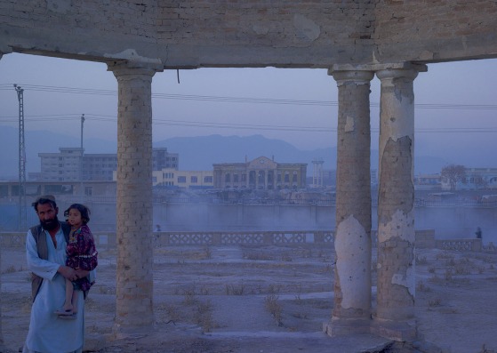 Jaw Aka Faizal Nahman y su hija Nono de la provincia de Bamiyan, ahora viven en un refugio de plástico improvisado en los jardines en ruinas del Palacio Darulaman. Construido en la década de 1920 para albergar un parlamento afgano, 'Darul Aman' se traduce como 'morada de paz'. Kabul, 2010 40x53" de una edición de 7 © Simón Norfolk 