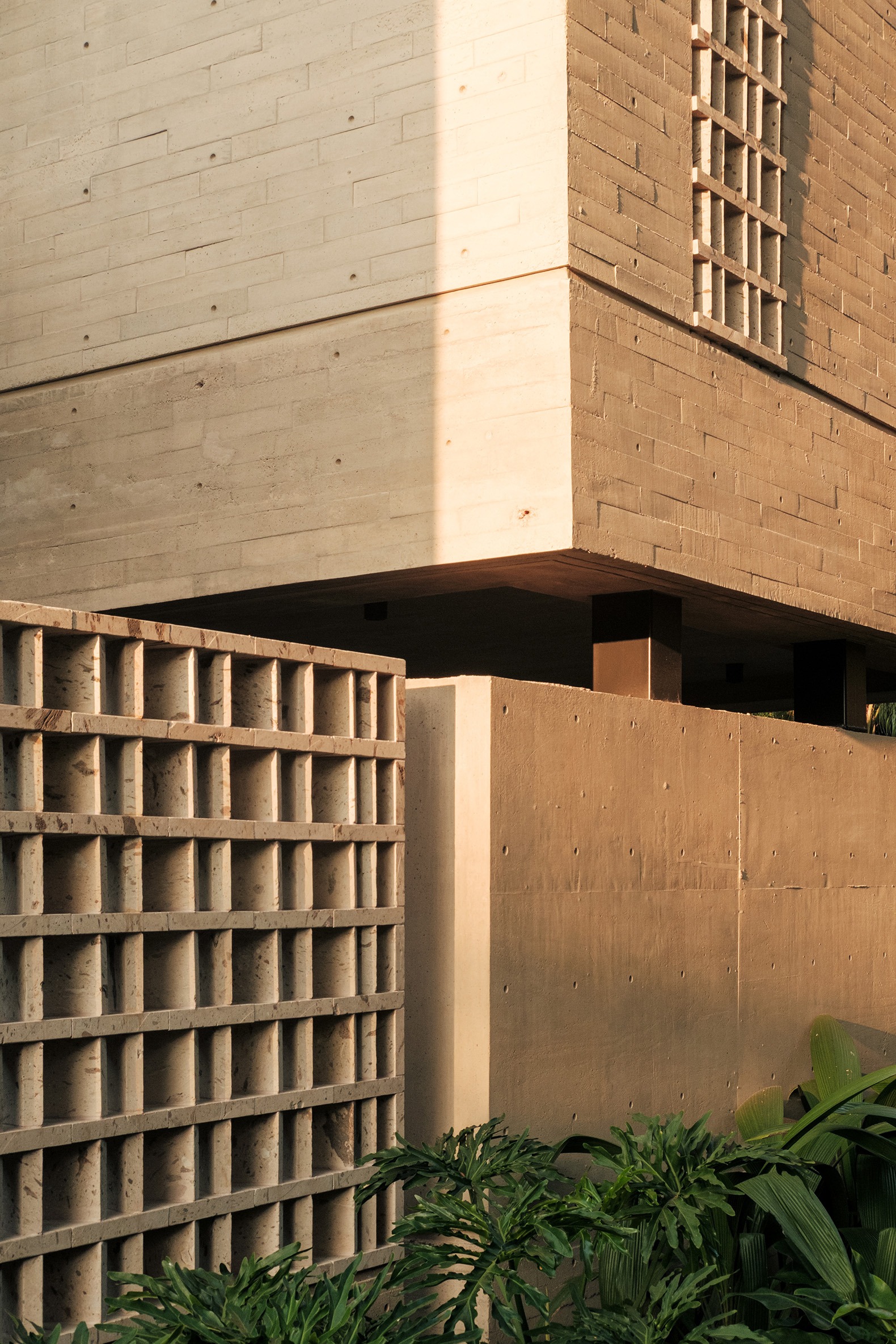 Casa Akina announces itself without fully revealing itself. Its presence is restrained, almost silent. Before unveiling its form, it allows light to filter through, lets vegetation peek in, and hints at the central void that organizes the layout. From the very first encounter, the architecture proposes a measured way of dwelling—one where the journey matters as much as the destination, and time itself becomes perceptible.  The house is built using a consistent material palette. Concrete, stone, and latticew