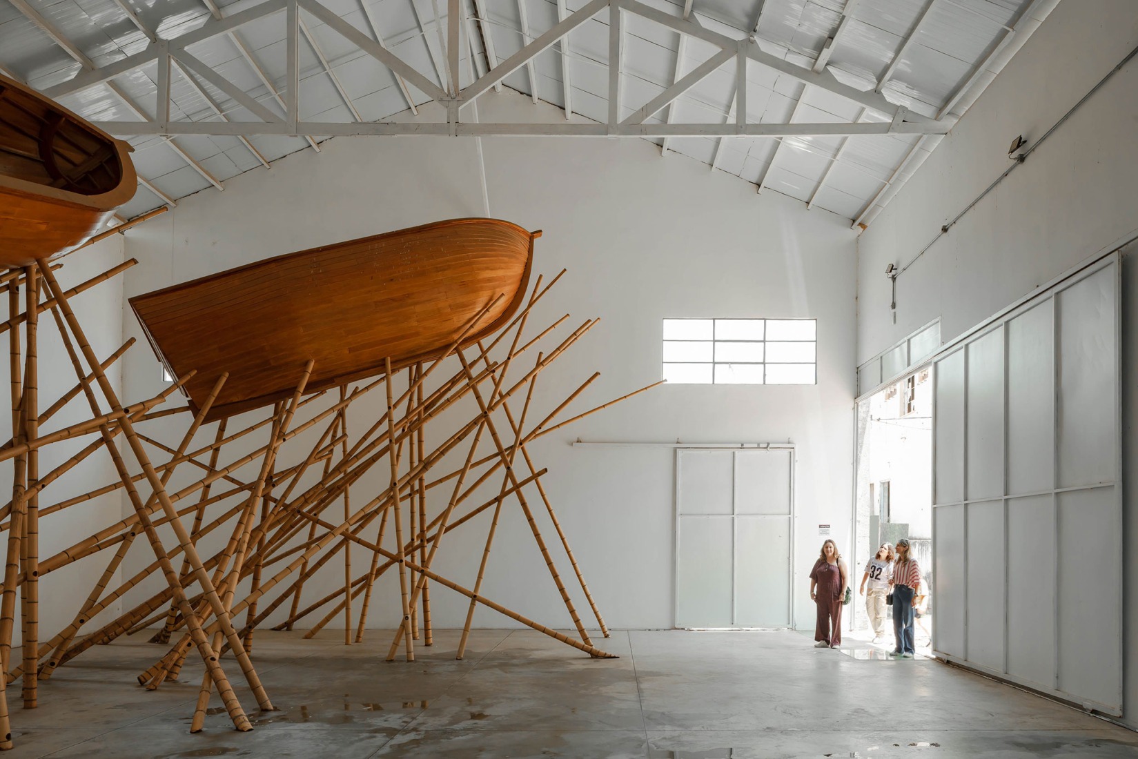 Interior view of the Exhibition Building J, featuring TIAMM SCHUOOMM CASH! (2016–2022) by José Spaniol Wooden boats and bamboo Variable dimensions. Fábrica de Arte Marcos Amaro (FAMA) by KAAN. Photograph by Sebastian van Damme.