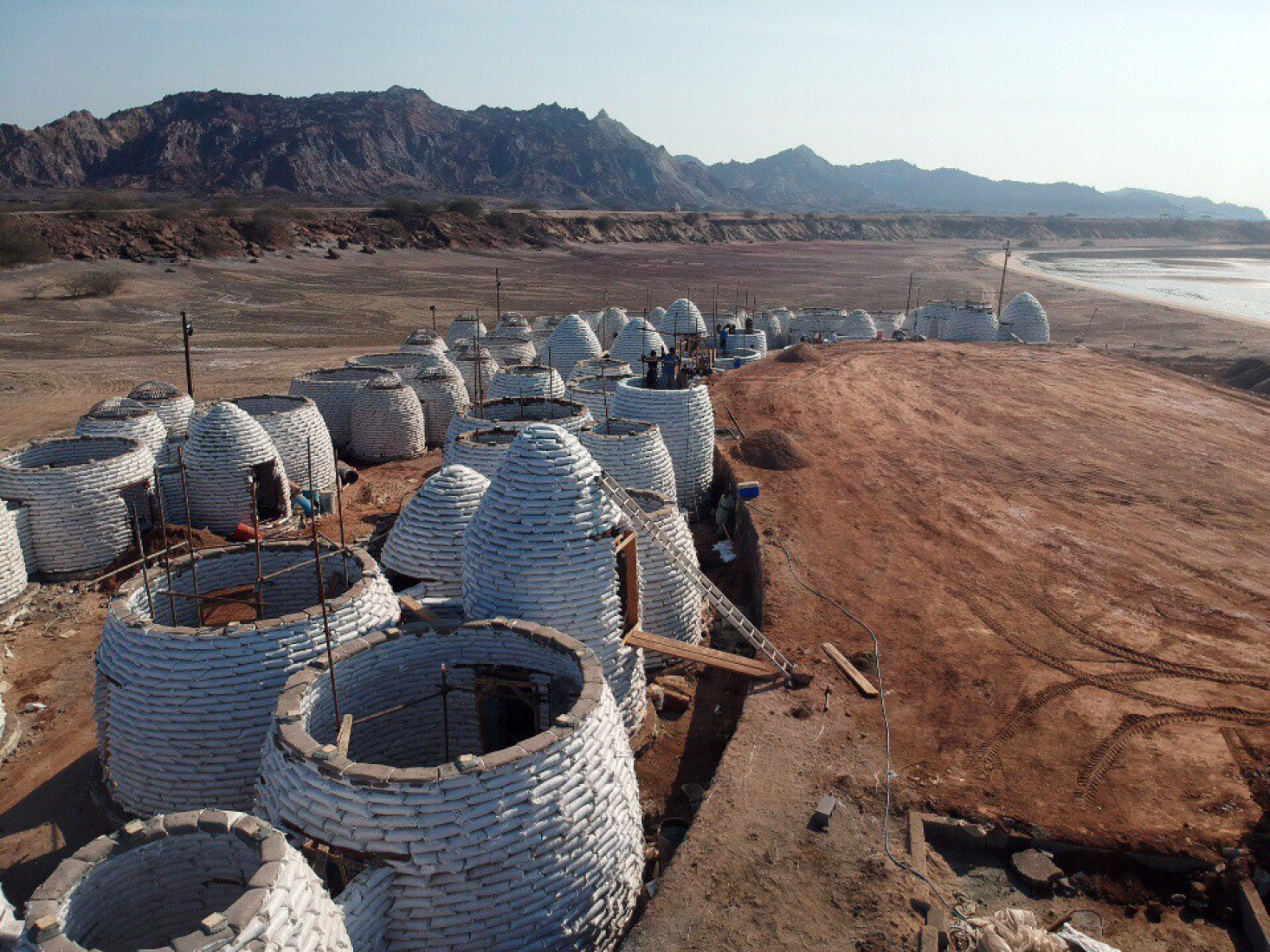 Majara Residence during construction. The domes were built using superadobe, a technique pioneered by Iranian architect Nader Khalili in the late 20th century, for which he received the Aga Khan Award for Architecture in 2004 (Sandbag Shelter). The construction method is suited to Hormuz’s climate and material availability. The thick earthen walls regulate indoor temperatures, reducing reliance on artificial cooling. Majara Residence and Community Redevelopment by ZAV Architects. Photograph by Deed Studio. Image courtesy of Aga Khan Trust for Culture. Majara Residence during construction. The domes were built using superadobe, a technique pioneered by Iranian architect Nader Khalili in the late 20th century, for which he received the Aga Khan Award for Architecture in 2004 (Sandbag Shelter). The construction method is suited to Hormuz’s climate and material availability. The thick earthen walls regulate indoor temperatures, reducing reliance on artificial cooling. Majara Residence and Community Redevelopment by ZAV Architects. Photograph by Deed Studio.