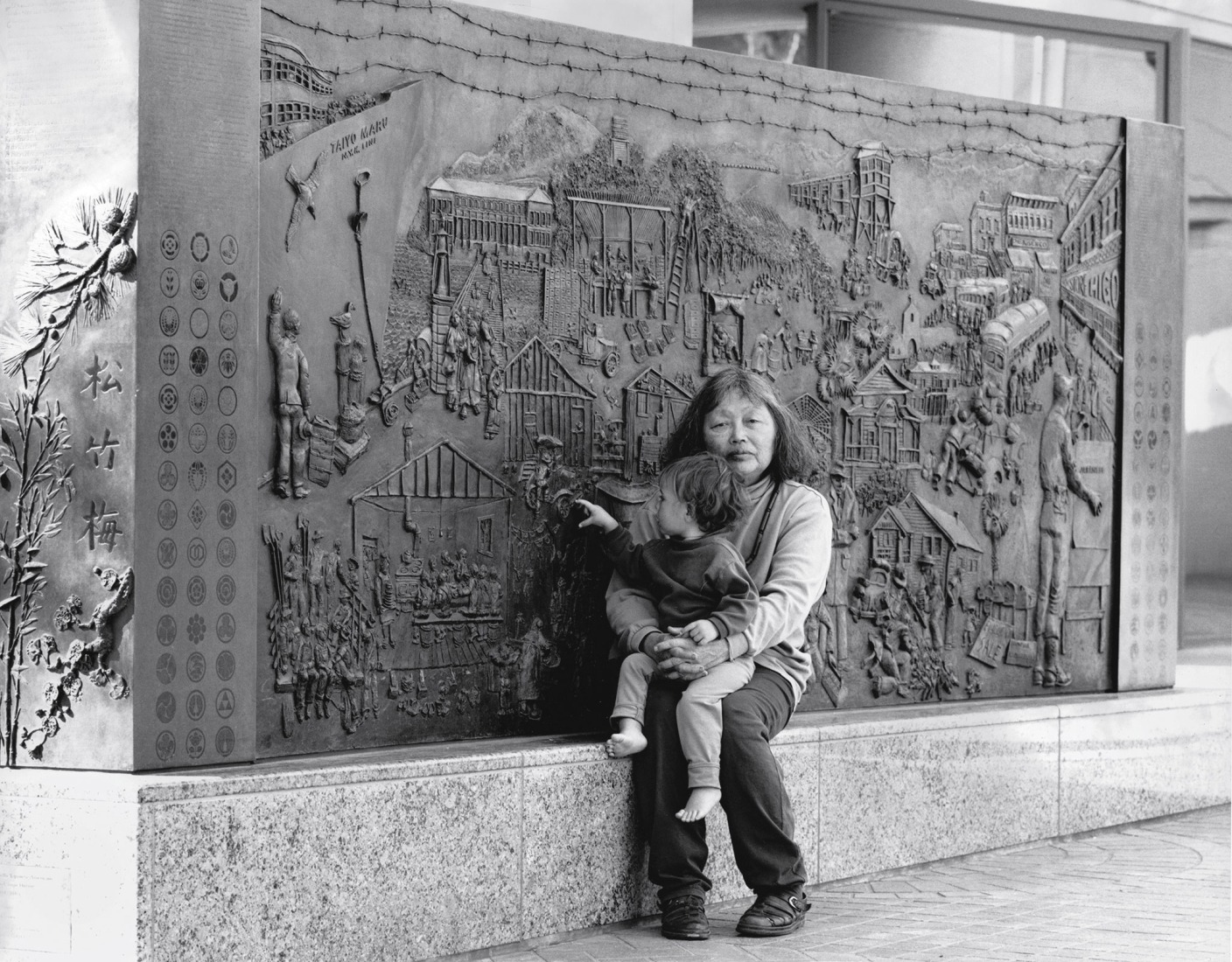 Ruth Asawa and her granddaughter at the Japanese US citizen Internment Memorial (PC.011), 1990-94, commissioned by the City of San Jose, 300 South First Street, San Jose. Copyright 2026 Ruth Asawa Lanier, Inc., Courtesy of David Zwirner. Photograph by Laurence Cuneo.