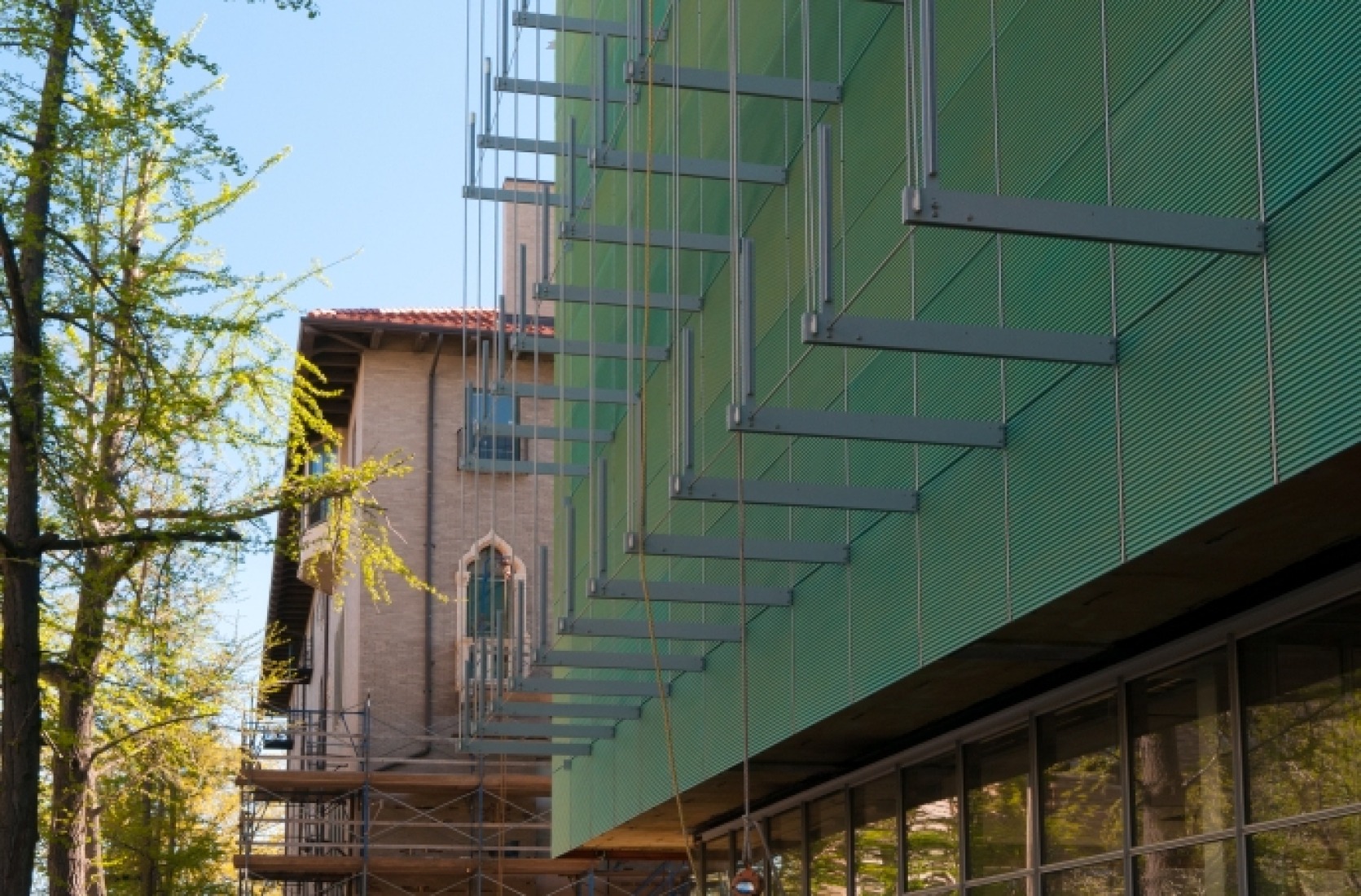Suspending Exterior Walkways. Suspended outriggers will support three levels of exterior walkways and a glass canopy that wrap around the performance hall volume.