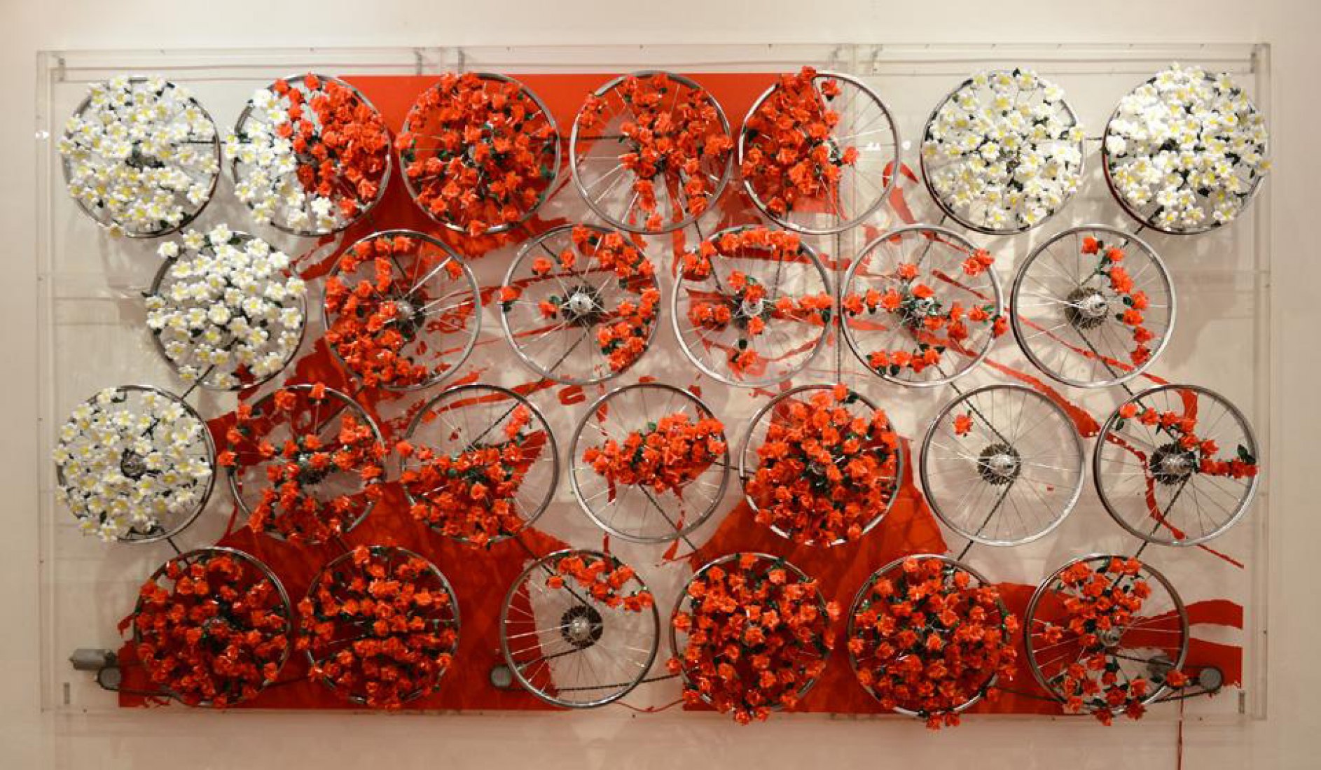Simplemente bellas, 2012, by Mabel Poblet Pujol. 200 x 300 x 15 cm., Plastic flowers, bicycle tires, electric motors, acrylic plates. Raquel Ponce Gallery.