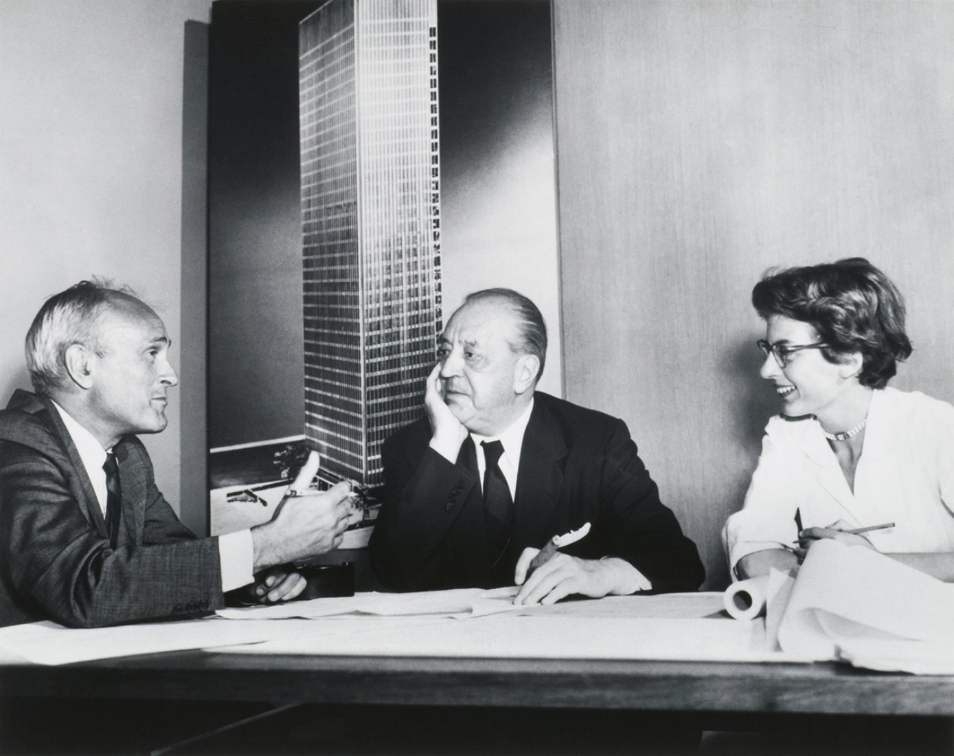 Philip Johnson, Ludwig Mies van der Rohe, and Phyllis Lambert in front of an image of the model for the Seagram building, New York, 1955. Gelatin silver print, 7 1/2 × 9 3/8 in. Photographer unknown. Fonds Phyllis Lambert, Canadian Centre for Architecture, Montreal. © United Press International.