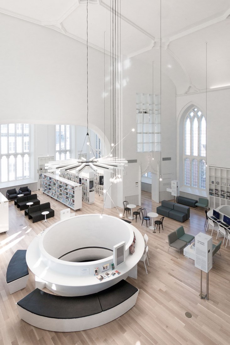 The large circular opening in the library’s floor and the hanging contemporary light fixture Maison. de la littérature (House of Literature) by Chevalier Morales Architectes. Photograph by Chevalier Morales Architectes. 