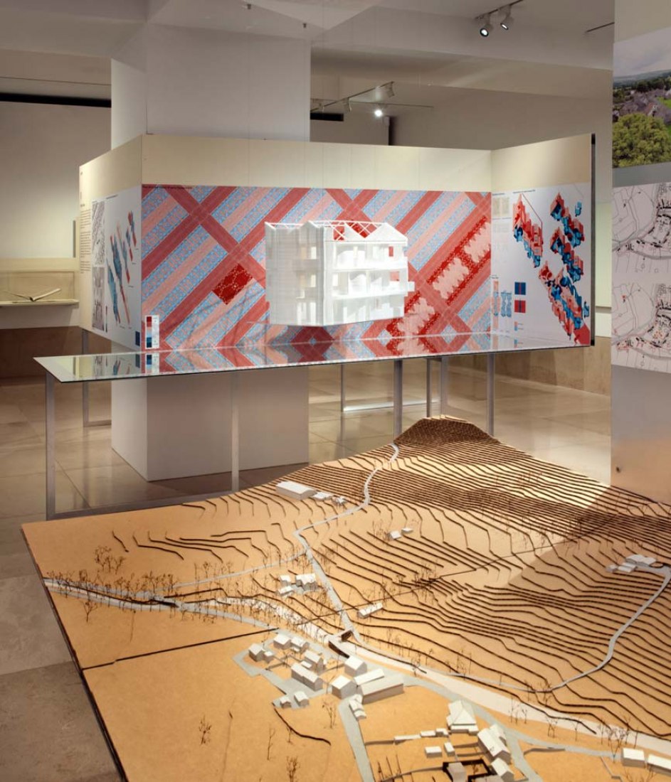 Vista de la instalación de la propuesta de Jamie Fobert para Como en casa en Gran Bretaña: Diseñando la casa del mañana. La'Casa de la Fiesta' de vPPr se puede ver al fondo. Fotografía © Philip Vile. Imagen cortesía de RIBA