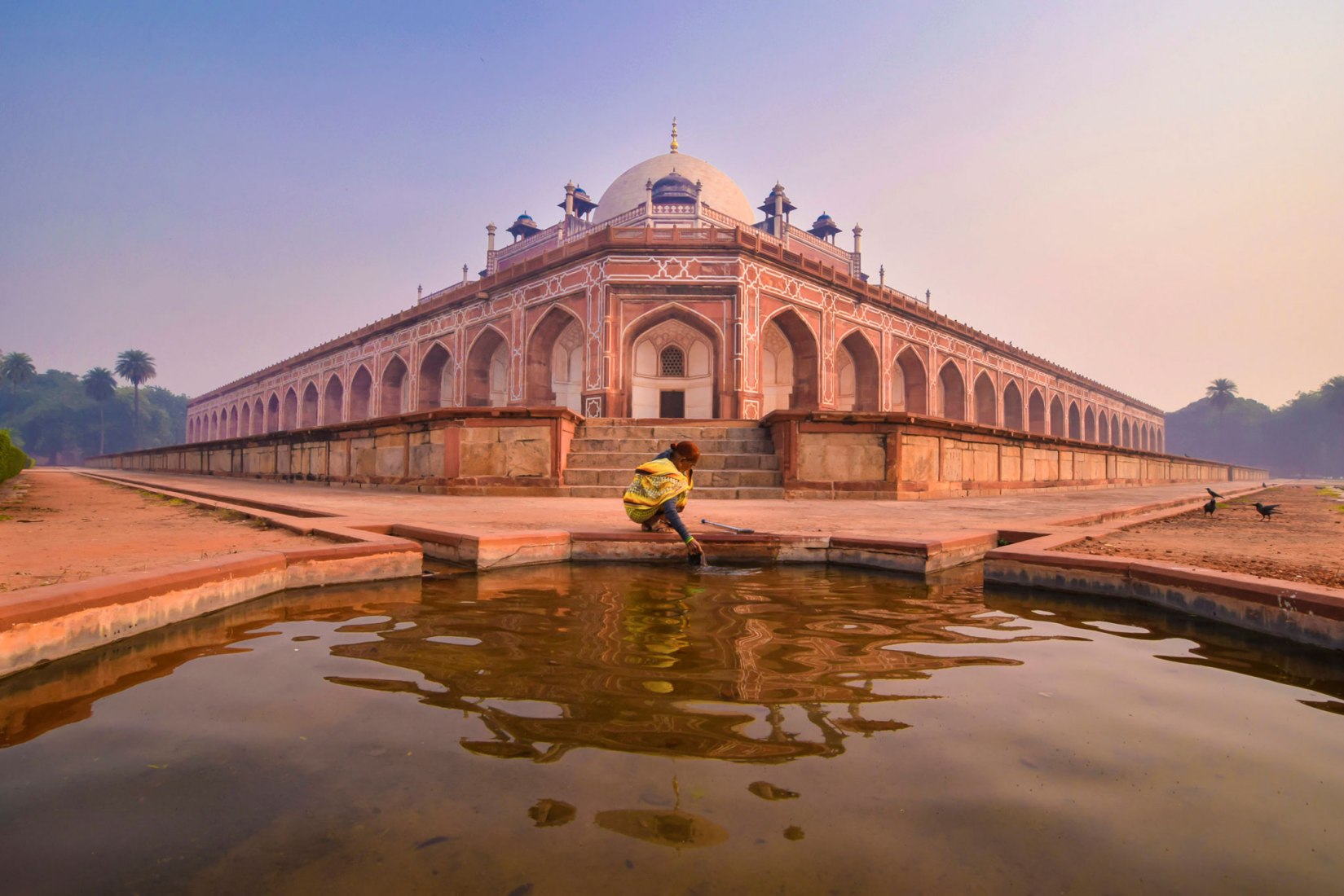 Ganador elegido por el público La vida a través de la historia  Fotógrafo: Sk Rahaman Hossain Cámara utilizada: Nikon D5300  Comentarios del fotógrafo: Tumba de Humayun, Delhi, India. Esperé aquí durante una hora y media para tomar esta foto. Lo que quería para la composición era una persona, era una mañana de invierno y no había nadie alrededor. De repente veo a una anciana y cuando se sentó a la orilla del agua capturé esta foto. Este espléndido mausoleo fue construido en memoria del emperador Humayun, el