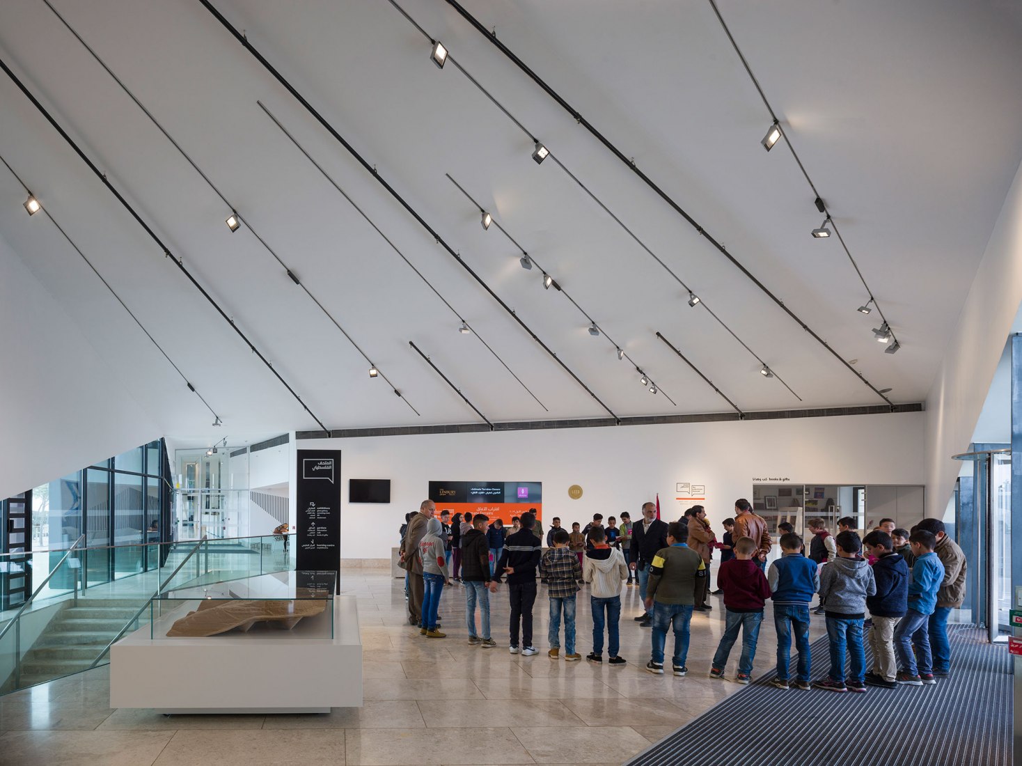 Grupo de escolares que esperan en el espacio de entrada central, que contiene una recepción, una tienda y una cafetería. Fotografía © Aga Khan Trust for Culture / Cemal Emden.