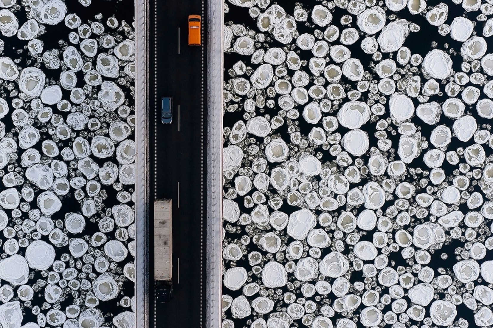 Profundo invierno. Polonia, Kiezmark. Un grupo de vehículos transita por un tramo en donde el hielo cubre al río Vistula cerca de la villa Kiezmark.Fotografía © Kacper Kowalski. 
