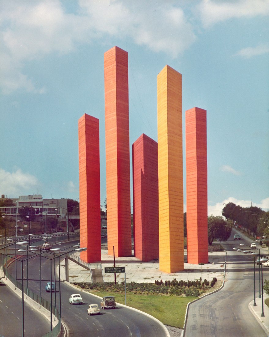 Luis Barragán and Mathias Goeritz, Torres de Satélite, Naucalpan de Juárez (Greater Mexico City), 1957. The photograph of the towers, painted in a palette of oranges and reds, was taken by Armando Salas Portugal in the late 1960s. Barragán Foundation. Photograph by Armando Salas Portugal / VG Bild-Kunst, Bonn 2022. Image courtesy of Vitra Design Museum.