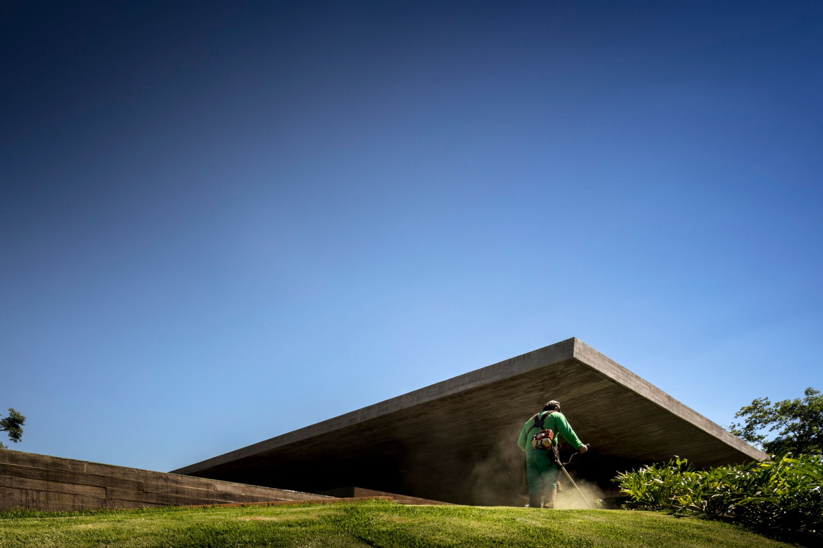 Jardinero cortando el césped. Casa Planar por Studio MK27 y Lair Reis. Fotografia por Fernando Guerra. FG+SG
