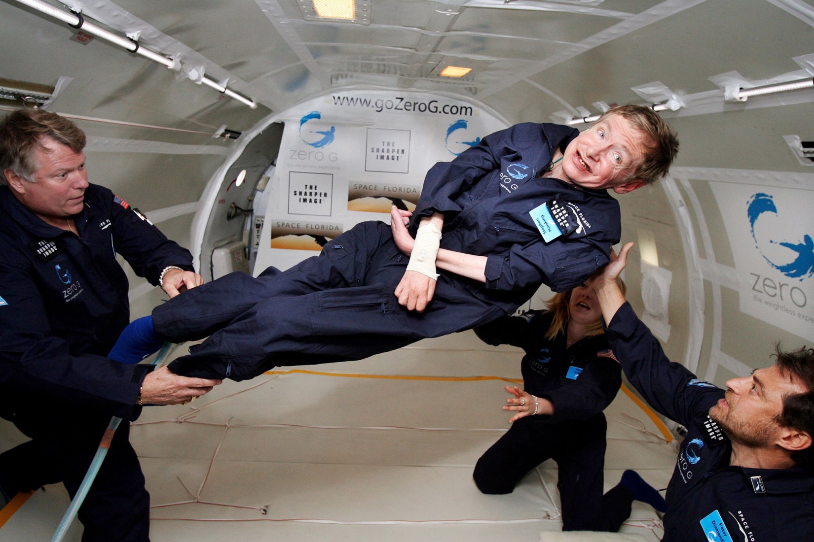 Stephen Hawking (center) enjoys zero gravity during a flight aboard a modified Boeing 727 aircraft owned by Zero Gravity Corp. (Zero G). Hawking is being rotated in air by (right) Peter Diamandis and (left) Byron Lichtenberg, former shuttle payload specialist. Kneeling below Hawking is Nicola O'Brien, is Hawking's aide. At his 65th birthday on January 8, 2007, Hawking announced his plans for a zero-gravity flight to prepare for a sub-orbital space flight in 2009 on Virgin Galactic's space service.