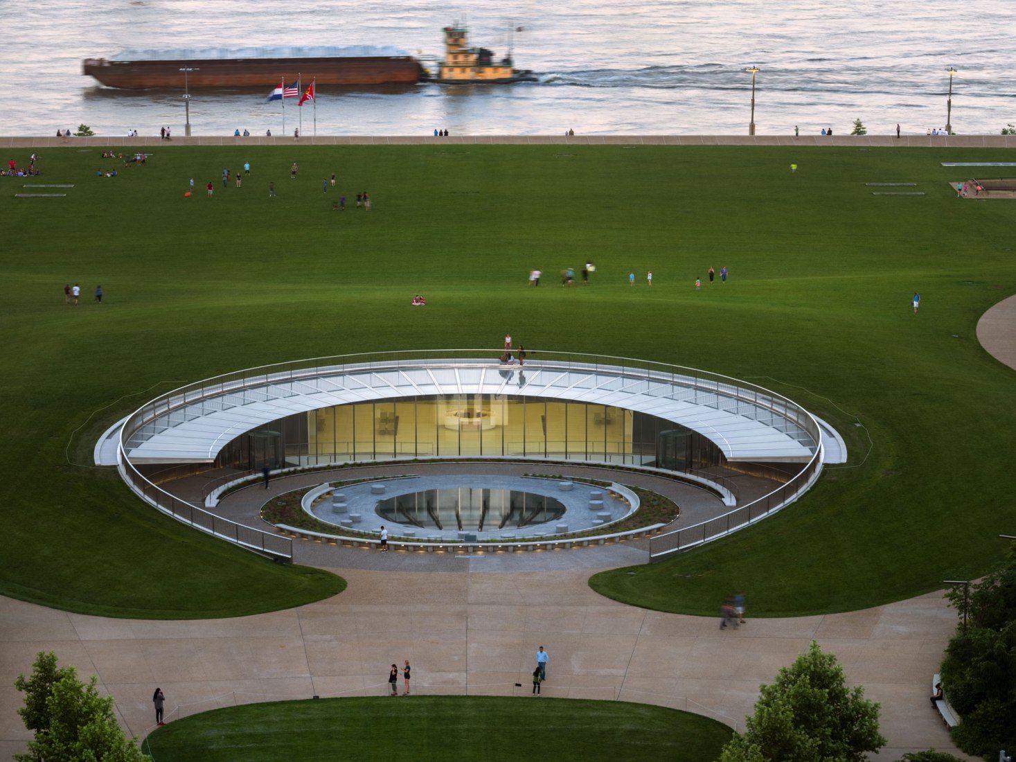 The materiality of the new West Entry Plaza of the Museum embraces the visitor in an arc of sky and the surrounding landscape, reflected by the diffused scrim of stainless steel screen walls. The tilt of this reflection references the Arch itself, intuitively leading visitors from the Plaza exterior into the Museum’s glassed-in entry volumes. Photograph by Nic Lehoux