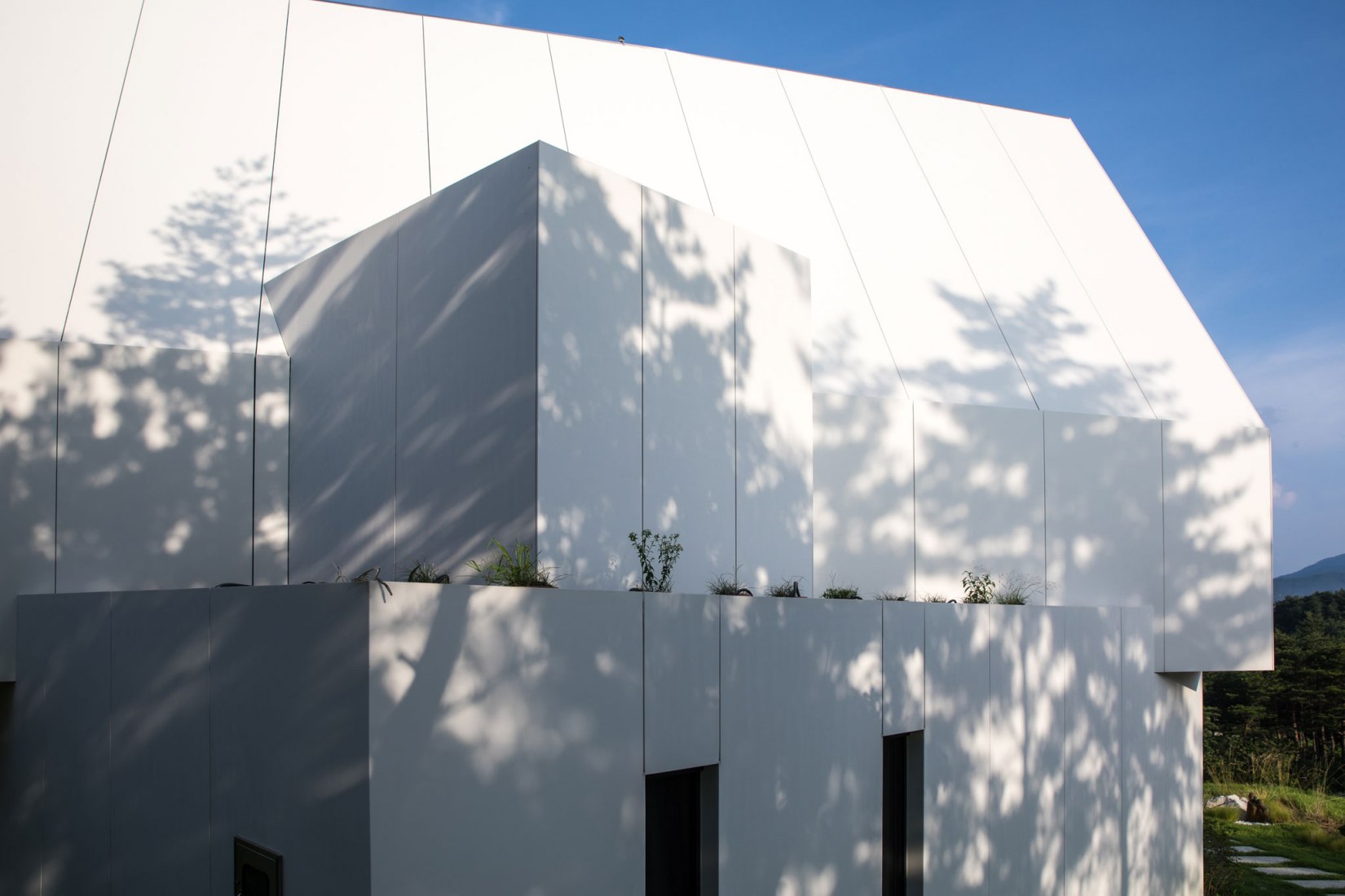 Facade detail. House [in white] by AEV Architectures. Photograph by Hyunjune Lee