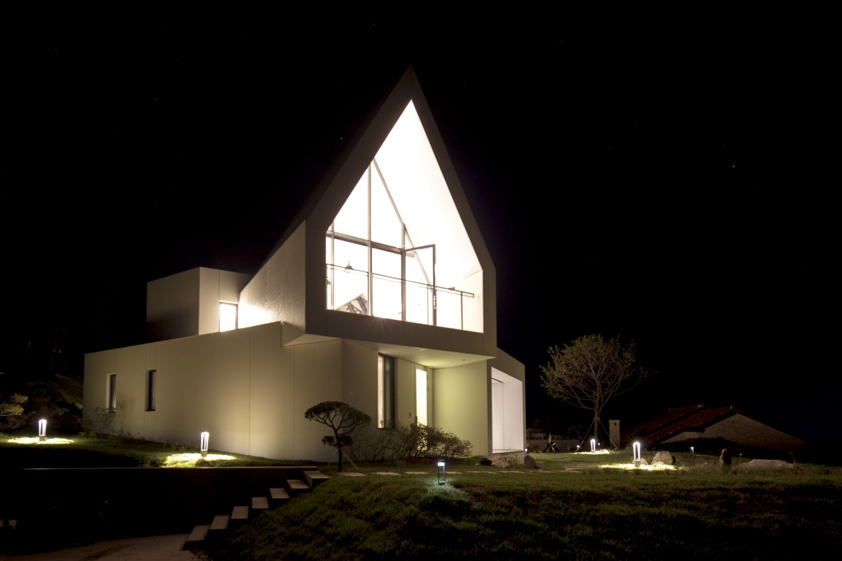 Night view. House [in white] by AEV Architectures. Photograph by Hyunjune Lee